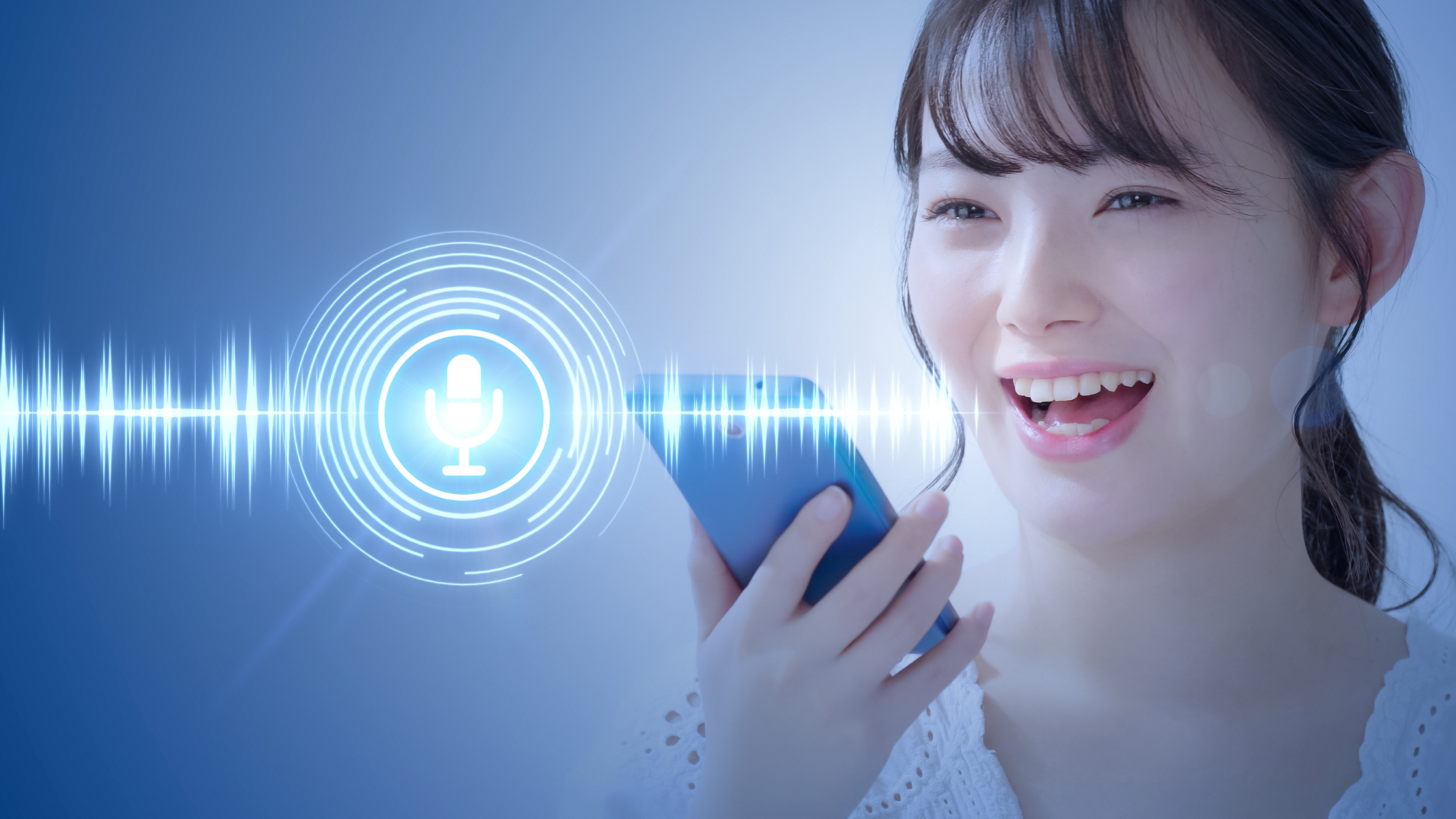 A person holding their phone up to their mouth with an overlay of a microphone and voice soundwaves in blue